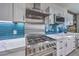 Close-up of a stainless steel stove with modern range hood, white countertops, and blue backsplash at 3305 Fernbird Ln, North Las Vegas, NV 89084