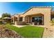 Backyard featuring an outdoor kitchen, covered patio, artificial grass, and desert landscaping at 4796 Riva De Romanza St, Las Vegas, NV 89135