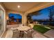 Covered patio with a dining table and view of the lush backyard at twilight at 4796 Riva De Romanza St, Las Vegas, NV 89135