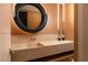 Modern bathroom featuring unique round mirror and stone vanity, with sleek fixtures at 4918 Summit Overlook Dr, Las Vegas, NV 89135