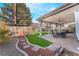 Backyard patio with an outdoor dining set, artificial turf, and desert landscaping at 4938 Via Luis Ct, North Las Vegas, NV 89031