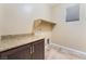 Well-lit laundry room features cabinets with granite countertops, a shelf, and tile flooring at 5648 Alitak Bay St, North Las Vegas, NV 89081