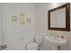 Neutral powder room featuring a pedestal sink, framed mirror, and decorative wall art at 6121 Sinatra Sands Ct, Las Vegas, NV 89130