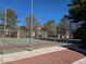 Outdoor community tennis court with fences, mature trees, and building in the background at 7200 Pirates Cove Rd # 1025, Las Vegas, NV 89145