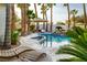 Tropical backyard with a large pool, waterfall, mature palm trees, and comfortable lounge seating at 8211 Windsor Crest Ct, Las Vegas, NV 89123