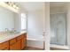 Bright bathroom featuring a bath tub, glass shower and white vanity with countertop at 8217 Maplestar Rd, Las Vegas, NV 89128