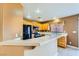A well-lit kitchen showcasing wooden cabinets, black appliances, and a breakfast bar with tile countertops at 8728 Honey Vine Ave, Las Vegas, NV 89143