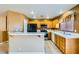 Bright kitchen featuring wood cabinetry, tile countertops, black appliances and an eat-in breakfast bar at 8728 Honey Vine Ave, Las Vegas, NV 89143