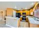 Kitchen with wood cabinets, black appliances, stainless steel stove, tile countertops, and breakfast bar at 8728 Honey Vine Ave, Las Vegas, NV 89143