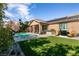 Inviting backyard featuring a sparkling pool, artificial grass, and an outdoor kitchen with a grill and comfortable seating at 10417 Artful Stone Ave, Las Vegas, NV 89149