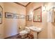 A well-lit powder room featuring a pedestal sink, decorative mirror, and framed artwork at 10700 Back Plains Dr, Las Vegas, NV 89134