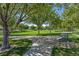 Picturesque view of a well maintained green community park with mature trees, paved walking paths, and comfortable benches at 11099 Moonlight Fire Ct, Las Vegas, NV 89135