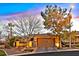 Charming home exterior with a well-manicured lawn and mature trees under a colorful sunset sky at 11099 Moonlight Fire Ct, Las Vegas, NV 89135