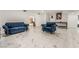 Spacious living room with an elegant blue velvet sofa and chair set, sleek tile flooring, and modern art at 1300 Oak Tree Ln, Las Vegas, NV 89108