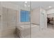 Luxurious bathroom showcasing a soaking tub, glass shower, tiled walls, and a glimpse into the walk-in closet at 3004 Barrett Springs Ave, Henderson, NV 89044