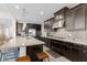 Modern kitchen featuring dark wood cabinetry, a light countertop island, and mosaic tile backsplash at 3004 Barrett Springs Ave, Henderson, NV 89044