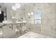 Modern bathroom with white marble tile, dual sinks, and a glass-enclosed shower at 4381 W Flamingo Rd # 903, Las Vegas, NV 89103