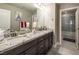 Bathroom featuring granite countertops, dark wood cabinets, a double sink, and a shower at 4612 Amazing View St, Las Vegas, NV 89129