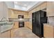 Bright kitchen featuring light wood cabinetry, granite countertops and black appliances at 62 E Serene Ave # 114, Las Vegas, NV 89123