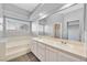 Bathroom featuring a double sink vanity, a soaking tub, and large mirror and ample lighting at 6652 Goldencreek Way, Las Vegas, NV 89108