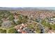 Expansive aerial view of a community with red tile roofs, lush trees, and mountain views in the distance at 7315 Mission Hills Dr, Las Vegas, NV 89113