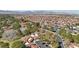 Expansive aerial view of a community with red tile roofs, lush trees, and mountain views in the distance at 7315 Mission Hills Dr, Las Vegas, NV 89113