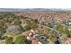 Expansive aerial view of a community with red tile roofs, lush trees, and mountain views in the distance at 7315 Mission Hills Dr, Las Vegas, NV 89113