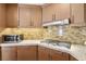Well-equipped kitchen featuring stainless cooktop, granite countertops, custom wood cabinets and tile backsplash at 7315 Mission Hills Dr, Las Vegas, NV 89113
