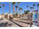A wrought iron gate entrance to a community lined with mature palm trees and desert landscaping on a sunny day at 8440 Wandering Sun Ave, Las Vegas, NV 89129