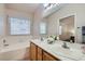 Bright bathroom with double sinks, a large mirror, and separate tub under a window at 1943 Chickasaw Dr, Henderson, NV 89002