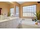 Bright bathroom showcasing white vanity, framed mirrors, modern fixtures, and a relaxing soaking tub at 283 New River Cir, Henderson, NV 89052