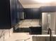 Renovated kitchen showcasing stainless steel appliances, marble countertops, and navy cabinets at 2970 Juniper Hills Blvd # 102, Las Vegas, NV 89142