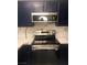 Close-up of a range oven under a microwave with dark blue cabinets, and white marble countertops at 2970 Juniper Hills Blvd # 102, Las Vegas, NV 89142