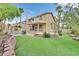 Manicured backyard with artificial turf, patio, and exterior elevation with mature landscaping at 3367 Trickling Stream Cir, Las Vegas, NV 89117