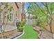 Green backyard with manicured landscaping, and a wrought-iron gate to a dog run at 3367 Trickling Stream Cir, Las Vegas, NV 89117