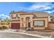 Two-story home featuring a red garage door, desert landscaping, and an arched entryway at 3401 Bedfordshire Pl, Las Vegas, NV 89129