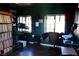 Dark home office offers a dedicated workspace with dark walls, hardwood floors, windows, and ample storage in the bookcase at 3780 E Kellogg Rd, Pahrump, NV 89061