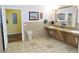 Accessible restroom with tan tile flooring and walls, featuring a long counter with two sinks and an adjacent doorway at 3780 E Kellogg Rd, Pahrump, NV 89061