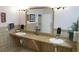 Well-maintained restroom featuring dual sinks, a large mirror, neutral tile, granite countertops, and decorative flowers at 3780 E Kellogg Rd, Pahrump, NV 89061