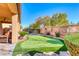 Scenic backyard featuring a putting green, lush plantings, and covered patio at 454 White Heart Rd, Las Vegas, NV 89148