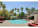 Expansive community pool area featuring palm trees, comfortable seating, and a scenic rock waterfall at 5250 S Rainbow Blvd # 2165, Las Vegas, NV 89118