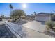 Single-story home with xeriscape yard, long driveway leading to a two-car garage, bathed in sunlight at 5305 Doe Ave, Las Vegas, NV 89146