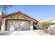 Tan single story home featuring a two car garage and desert landscaping at 6533 Adonis Heights Ave, North Las Vegas, NV 89086