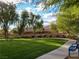 Community green space with mature trees, walking path, bench seating, and residential homes at 6533 Adonis Heights Ave, North Las Vegas, NV 89086