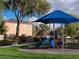 Community playground featuring a blue shade structure over play equipment with homes in the background at 6533 Adonis Heights Ave, North Las Vegas, NV 89086