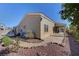 Backyard view of tan home featuring covered patio, red rock landscaping, and mature trees at 7331 Abundant Harvest Ave, Las Vegas, NV 89131