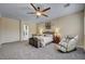 Bright main bedroom with a ceiling fan, neutral carpet, massage chair and chest at the foot of the bed at 7331 Abundant Harvest Ave, Las Vegas, NV 89131