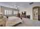 Spacious main bedroom featuring two windows, a ceiling fan, carpet floors and a door leading to the bathroom at 7331 Abundant Harvest Ave, Las Vegas, NV 89131
