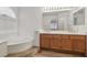 Bathroom with a large tub, wood cabinets, and a dual sink vanity at 7501 Bush Garden Ave, Las Vegas, NV 89129