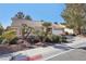 A charming single-story home with desert landscaping features a tile roof and mature trees at 7501 Bush Garden Ave, Las Vegas, NV 89129